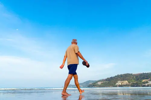 Man striding on a beach under a blue sky